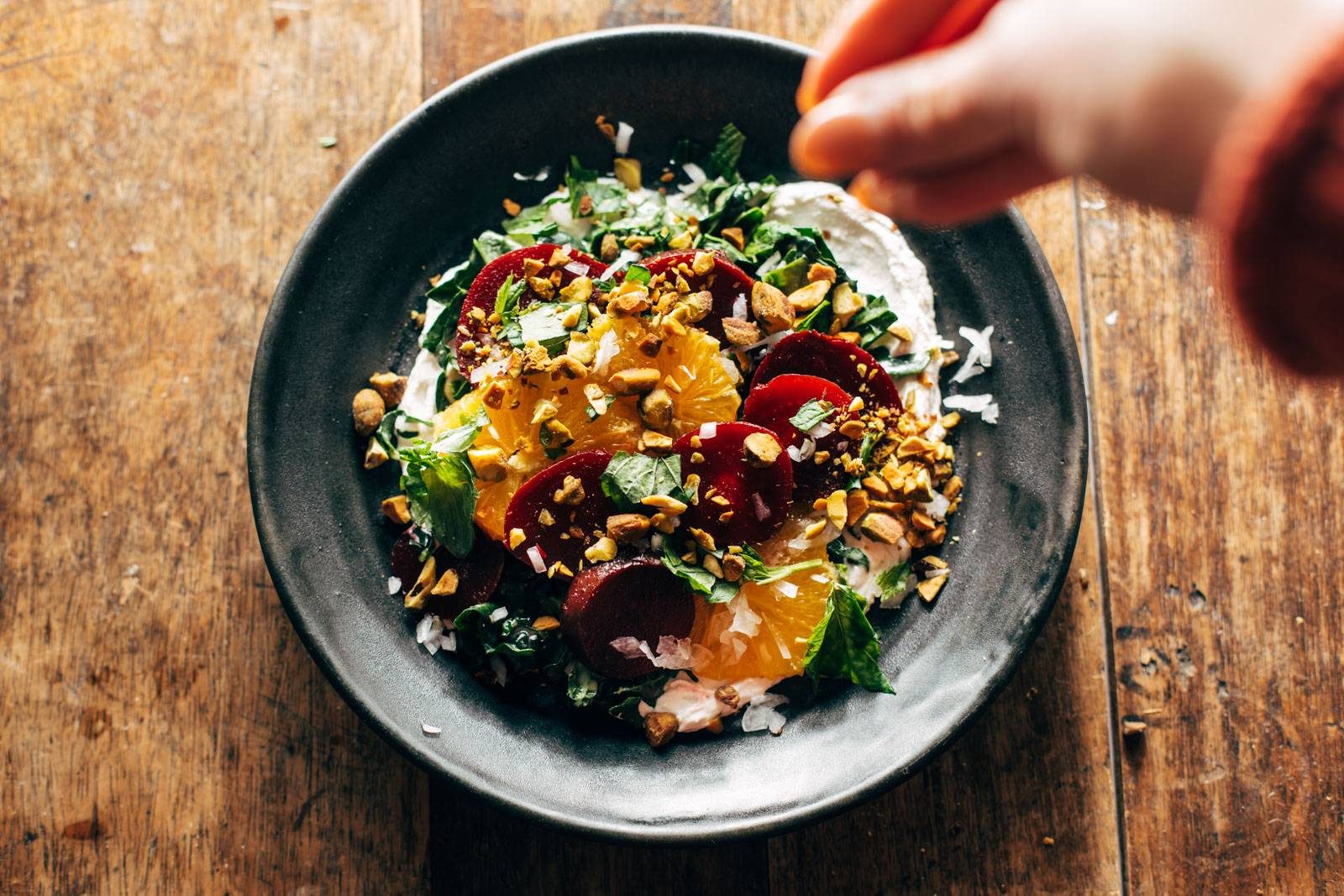 Sprinkling pistachios on a salad.