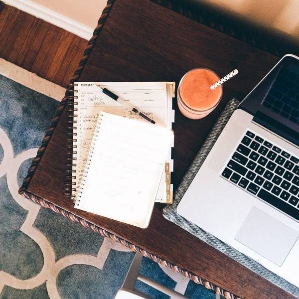 Notepads next to a smoothie on a desk.