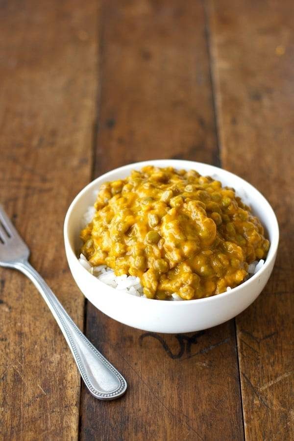 Kabocha Squash Lentil Curry in a white bowl on a wooden surface.