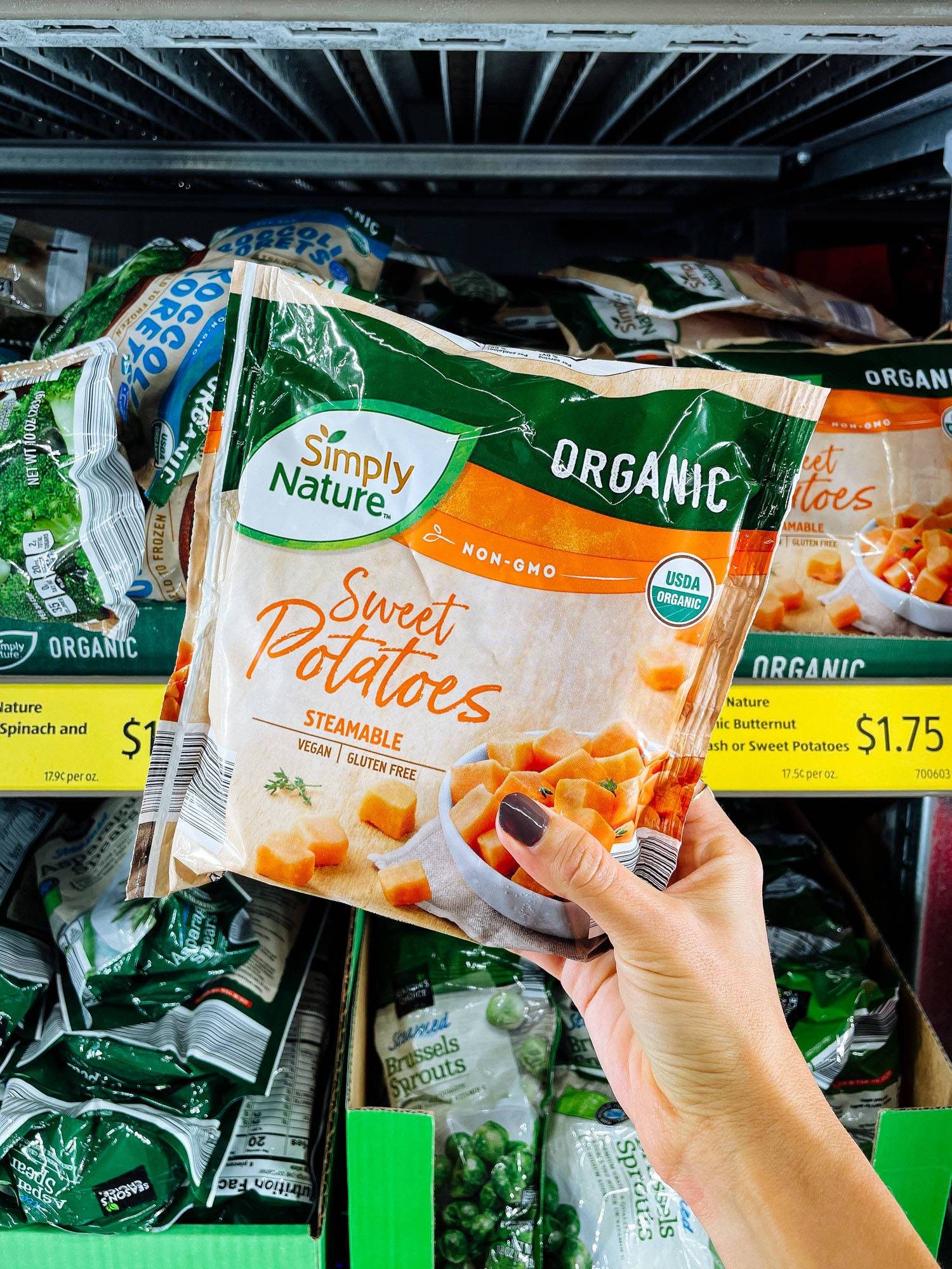 White hand holding frozen sweet potatoes from ALDI.