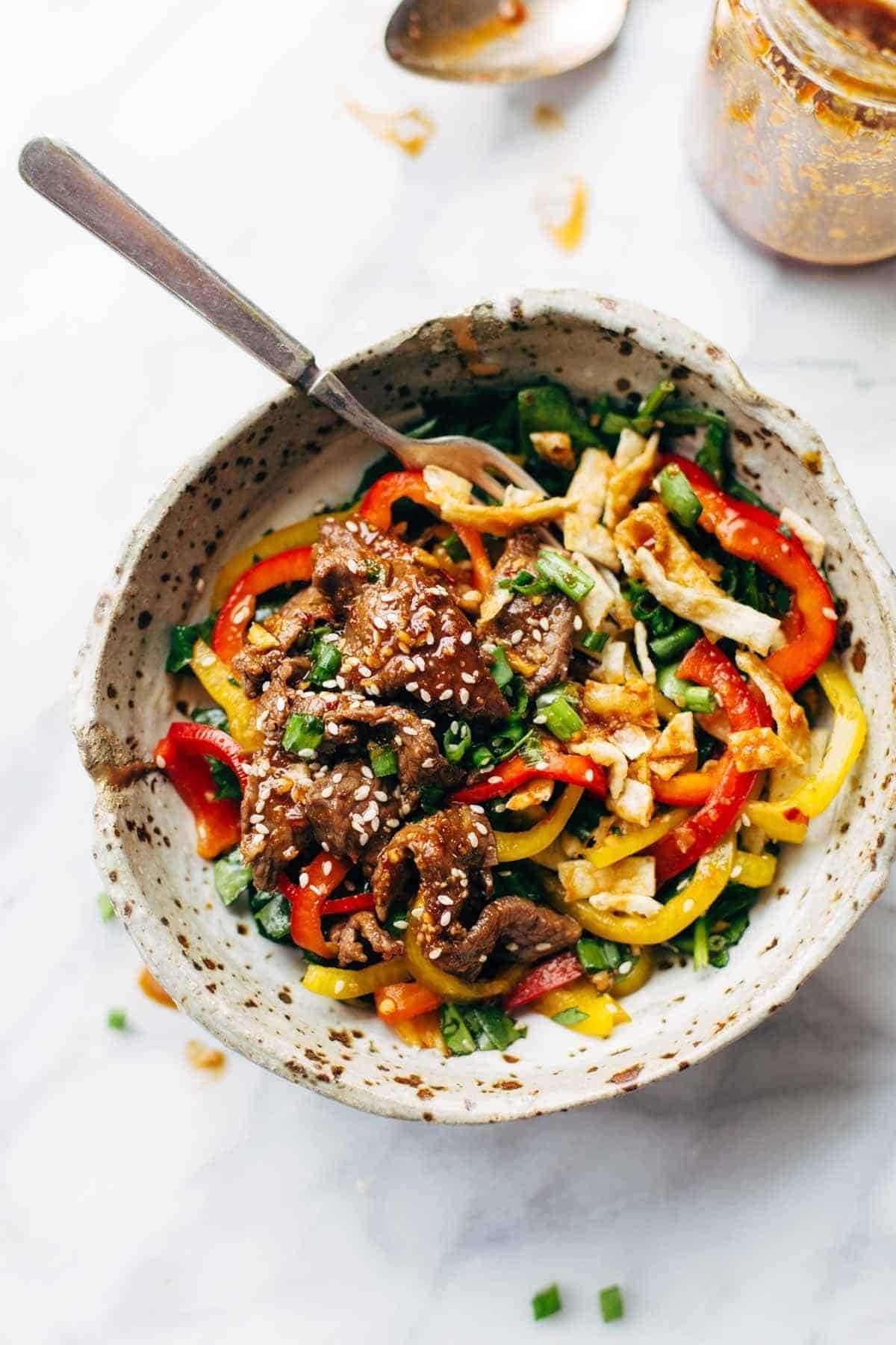 Korean BBQ Steak Bowls! Featuring Korean BBQ steak, bell peppers, scallions, greens, wonton strips, a spicy sesame ginger dressing. | pinchofyum.com