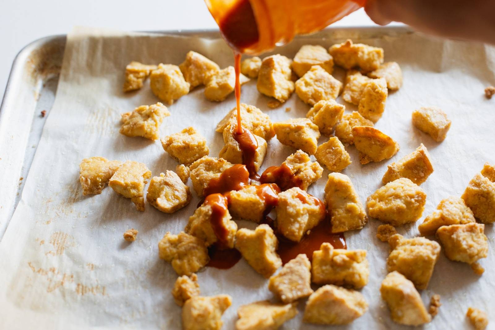 Pouring sauce on baked crispy tofu.