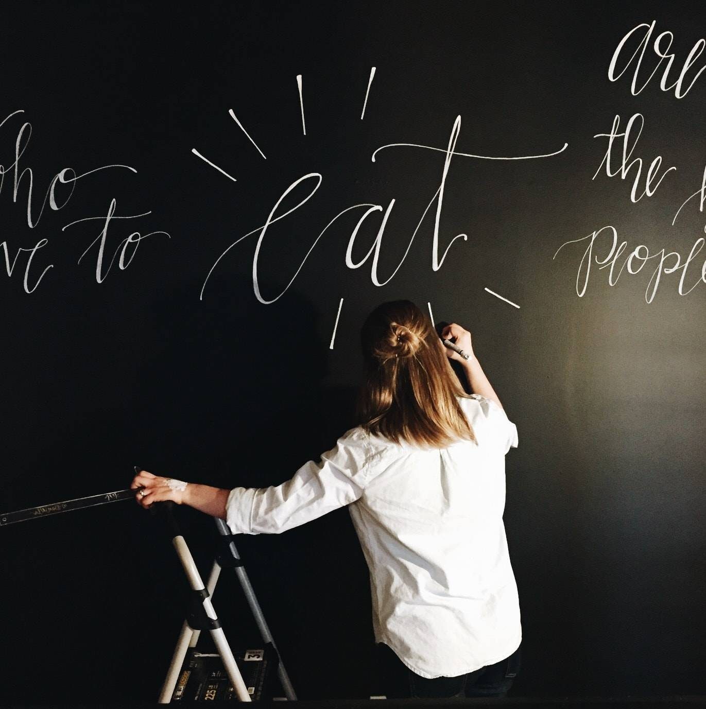 girl drawing on a black surface with a white marker