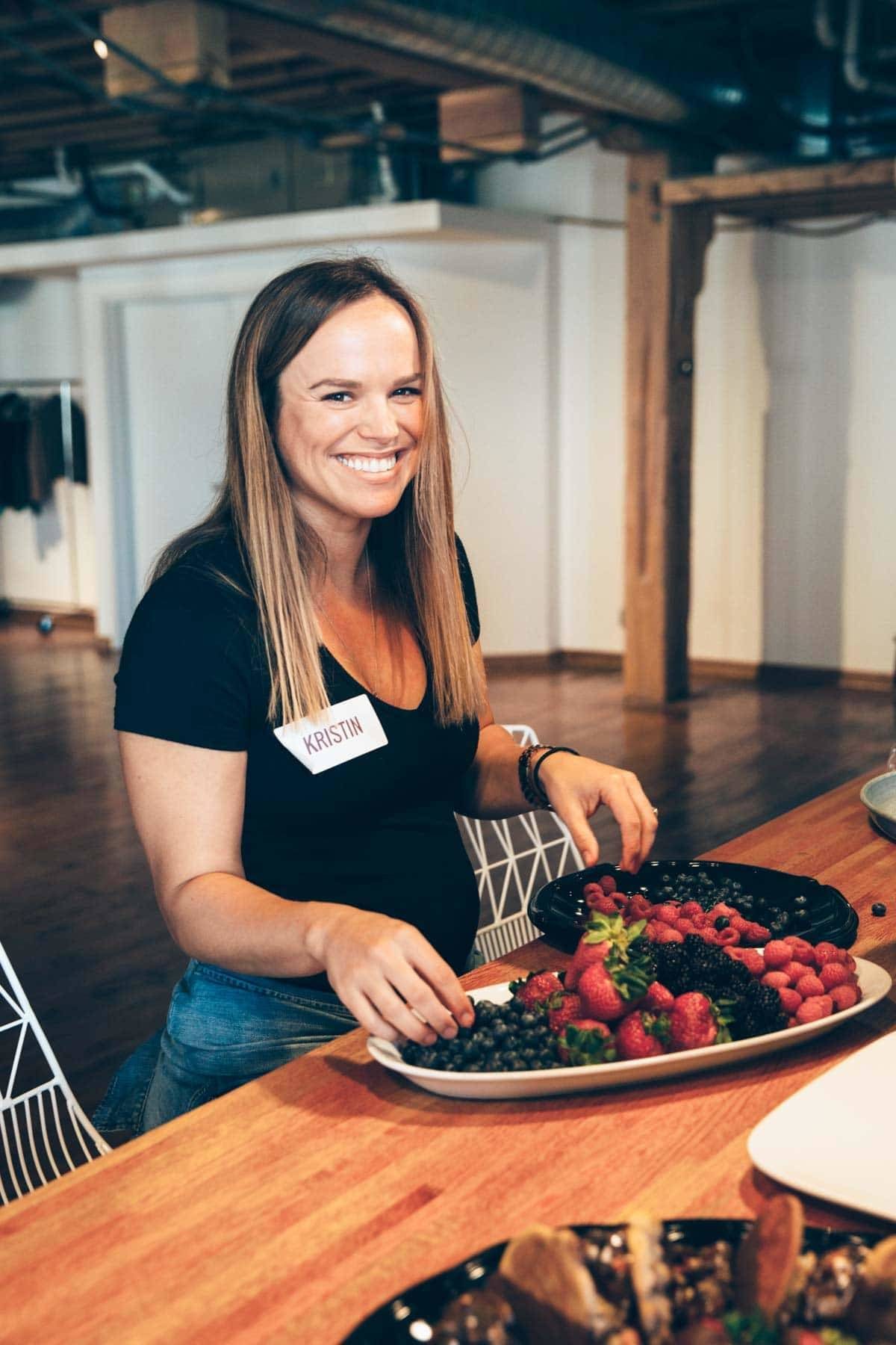 Woman grabbing fruit from a bowl.