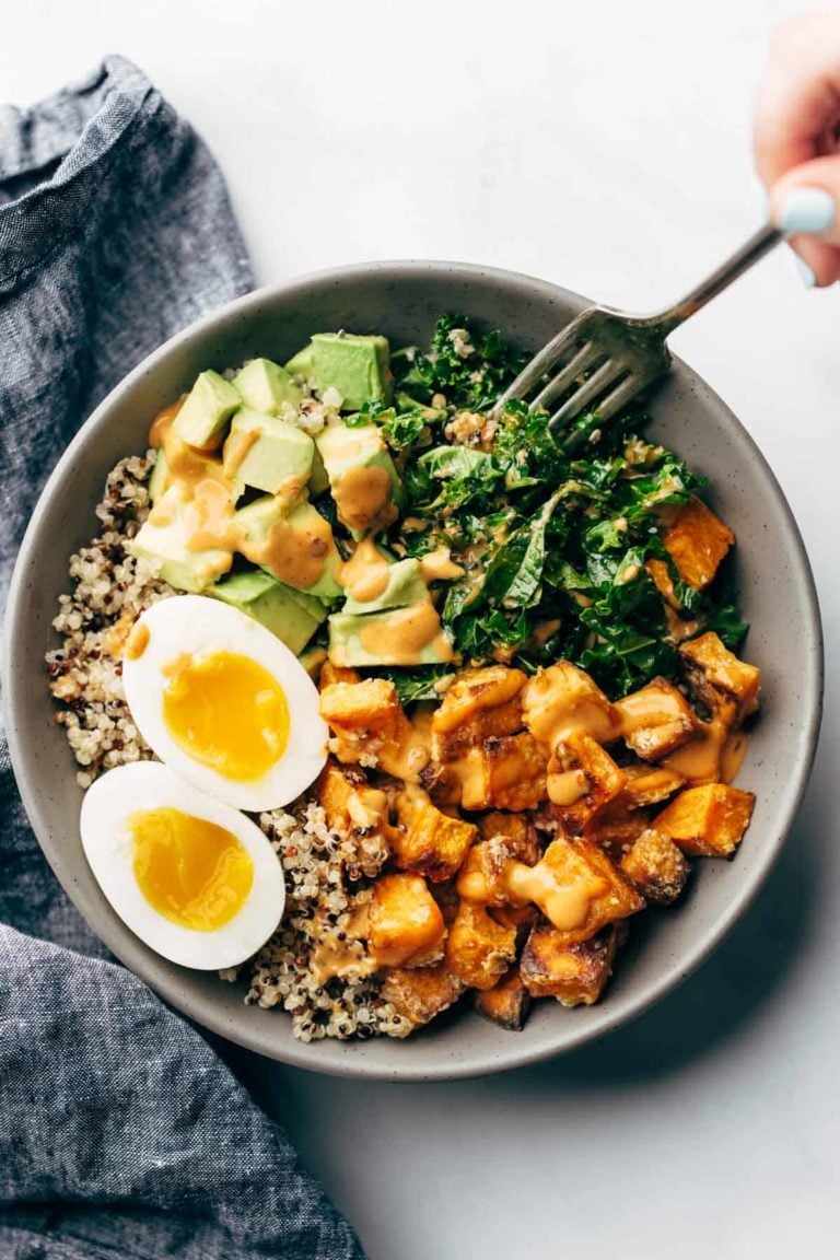 Bowl with sweet potatoes, quinoa, kale, avocado, egg, and chipotle tahini.