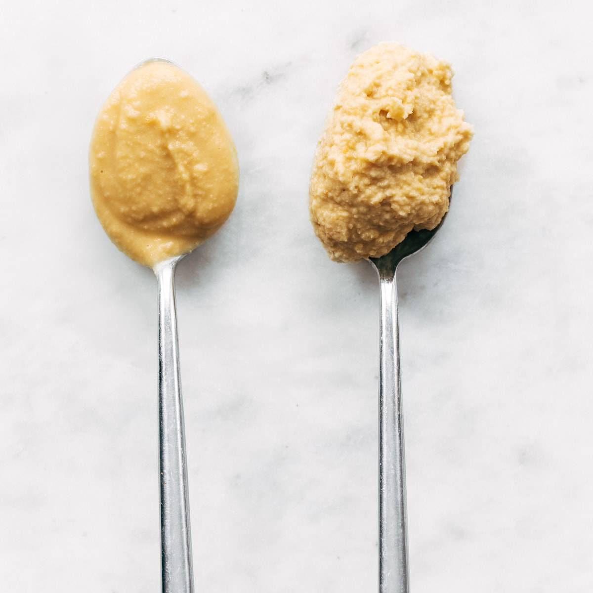 Smooth and coarse hummus on spoons.