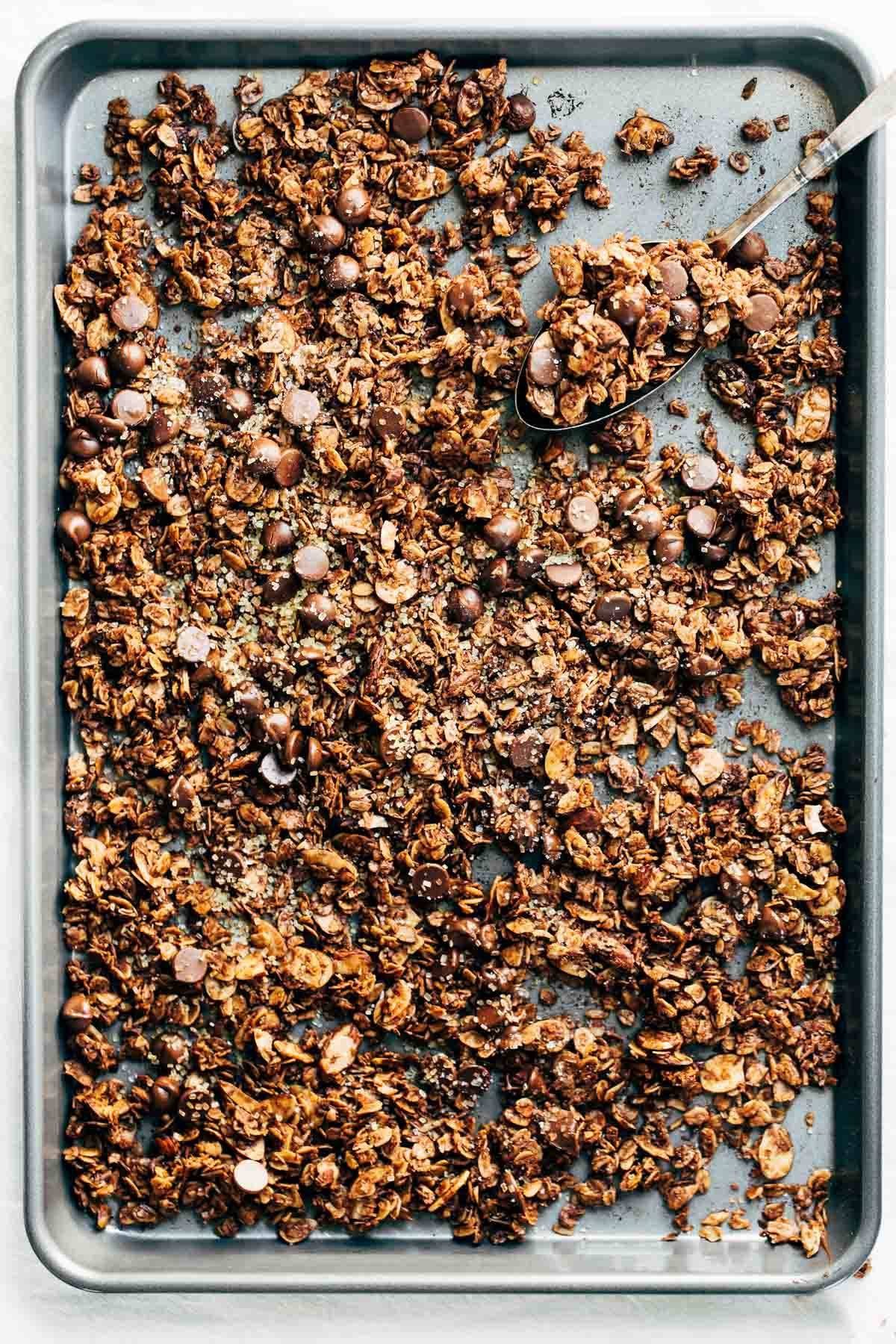 Chocolate Granola on a sheet pan with a spoon.
